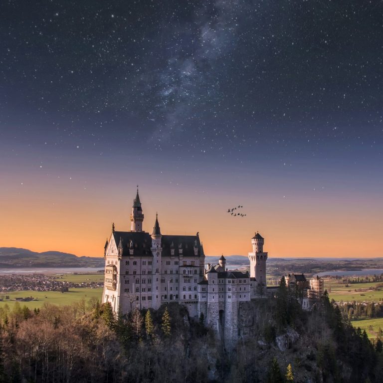 Neuschwanstein Castle unter dem Sternenhimmel bei Sonnenuntergang.