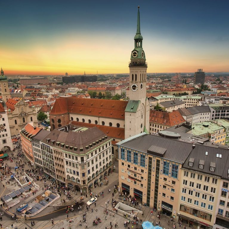 Blick auf eine Stadt mit historischen Gebäuden und einem Turm bei Sonnenuntergang.